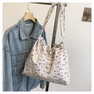 Détail du sac bandoulière en toile florale avec cordon de serrage et large bandoulière