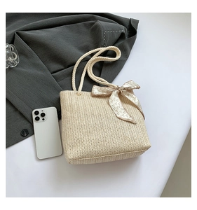 Détail du sac cabas en paille avec texture à chevrons, anses en corde et foulard à cœurs