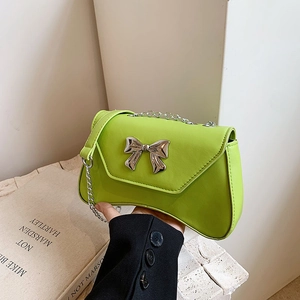 Lime green shoulder bag with silver metallic bow and chain strap in a stylish scene