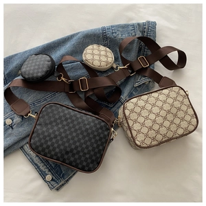 Detail view of plaid patterned camera bag set with round coin purse and wide strap on denim jacket