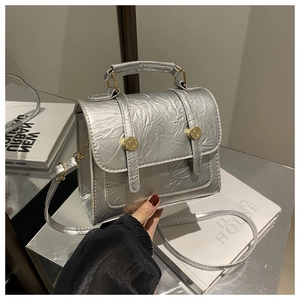 Detail of silver textured handbag with golden ring buckles and top handle