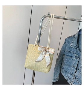 Détail d'un sac cabas en paille tissée avec poignées en corde blanche et foulard imprimé