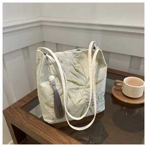 Dettaglio ricamo bambù su borsa tote jacquard con nappa grigia e perline di legno