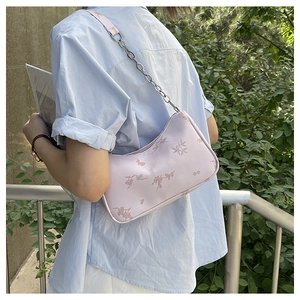 Pink butterfly hobo bag with floral print and silver chain strap shown in outdoor setting