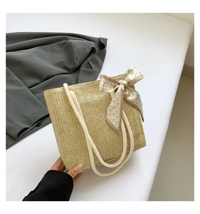 Détail du sac cabas en paille tissée beige avec poignées en coton et foulard en soie