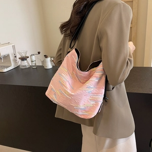 Sac hobo rose avec broderies abstraites et bandoulière noire porté par un mannequin chic