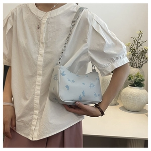 Detail of light blue crossbody bag with vintage butterfly pattern and silver chain strap