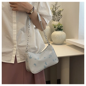 White butterfly pattern shoulder bag with silver chain detail on model in home setting