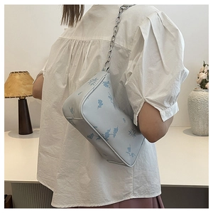 Detail of light blue floral embroidery and silver chain strap on square shoulder bag