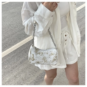 Détail du sac bandoulière blanc à motif papillon avec bandoulière en chaîne argentée