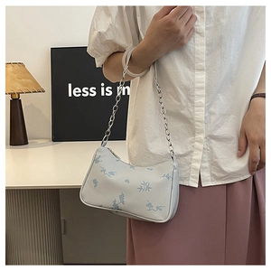 Light blue floral shoulder bag with thick silver chain worn by a model in a modern setting