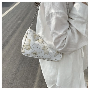 Détail d'un sac à bandoulière blanc avec imprimé papillon doré et bandoulière chaîne