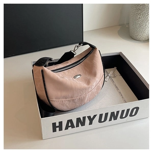 Detail of pink pleated nylon crescent bag featuring black trim and silver hardware