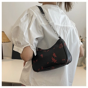 Detail of a black crossbody bag with red floral embroidery and silver chain strap