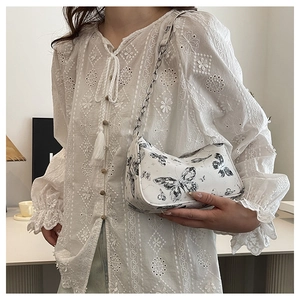 Détail du sac à bandoulière blanc imprimé papillon avec chaîne en métal argenté