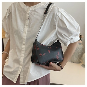 Detail of black shoulder bag with red floral embroidery and silver chain strap