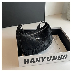 Close-up of black wrinkled texture crossbody bag with silver zipper and metallic logo