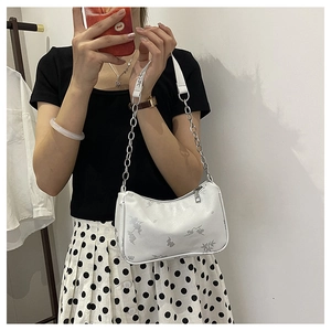 Detail of white floral print shoulder bag with silver chain strap and zipper closure