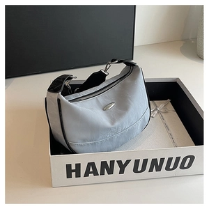 Detail of grey half-moon crossbody bag with silver oval hardware and wide strap