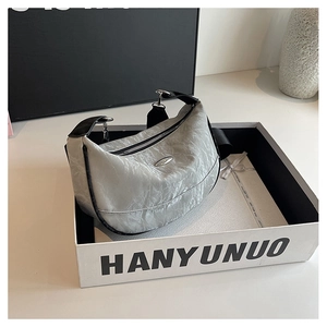 Detailed macro view of silver crescent bag with pleated texture and black contrast piping