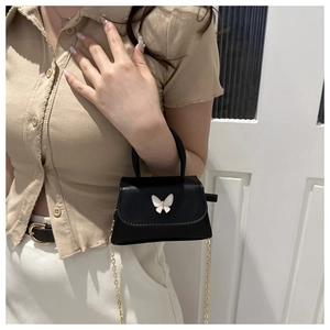 Mini black leather crossbody bag featuring a white butterfly buckle and golden chain strap