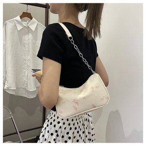 Detail of crossbody bag featuring pink floral prints and silver chain strap on model
