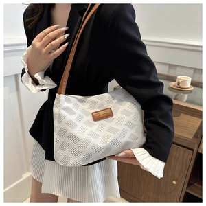 Detail of white woven tote bag with brown leather straps and vintage logo patch