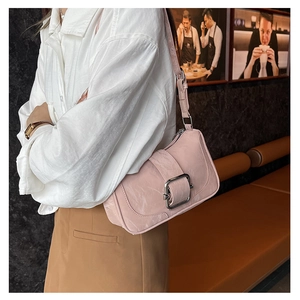 French style light pink shoulder bag with silver buckle worn by a model in a cafe
