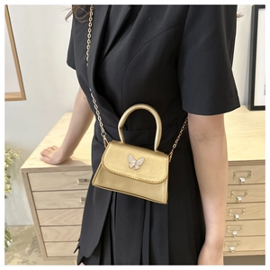 Detailed macro view of the golden mini bag with white bow accent and fine chain strap