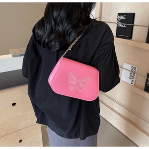 Détail du sac bandoulière rose avec broderie papillon et bandoulière chaîne dorée