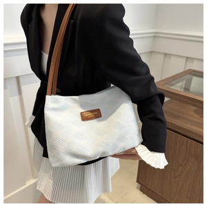 Detail of jacquard fabric texture and leather logo tag on a stylish shoulder bag
