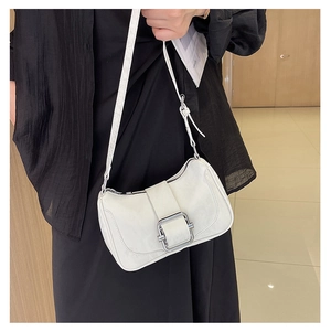Detail of white leather shoulder bag featuring a square silver buckle and adjustable strap