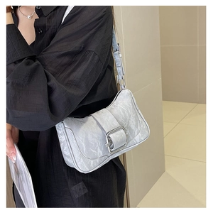 Detail view of silver-gray metallic pleated bag with large square chrome buckle
