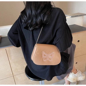 Détail du sac bandoulière kaki avec broderie papillon rose et bandoulière chaîne