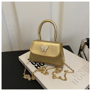Detail view of the shimmering gold mini bag with a white butterfly ornament and chain strap