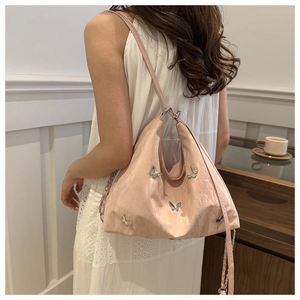 Detail van lichtroze metallic tas met zilveren vlinders en een schouderketting