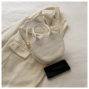 Detail shot of mini white crocodile pattern bag showing texture and size with a phone