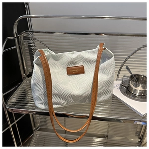 Detailed close-up of textured fabric pattern and leather logo tag on a tote bag