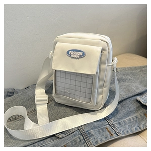Détail du sac à bandoulière en nylon blanc avec étiquette mode et fenêtre sur denim