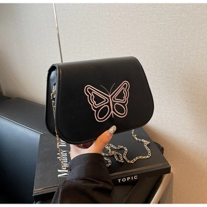 Détail du sac bandoulière en cuir noir avec broderie papillon rose et chaîne dorée