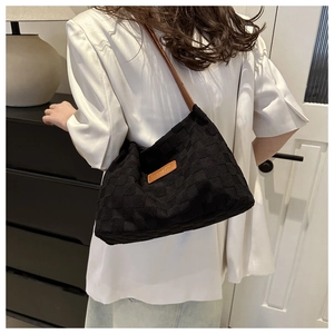 Close-up of black woven nylon tote featuring checkered texture and brown leather patch