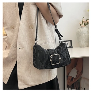Detail of black pleated shoulder bag featuring a large silver metallic square buckle