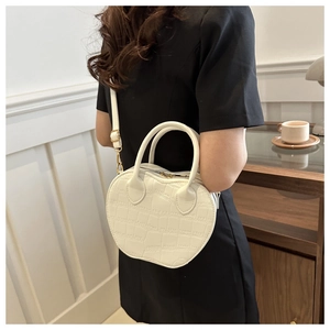 Detail of white heart-shaped handbag with crocodile embossed leather and gold hardware