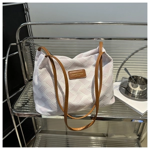 Detail showing woven texture and brown leather tag on minimalist tote bag for women