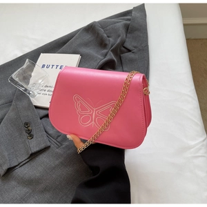 Détail du sac en similicuir rose avec broderie papillon élégante et bandoulière dorée