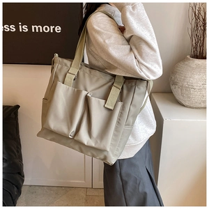 Detail of light khaki nylon tote bag featuring front slip pockets and durable webbing straps