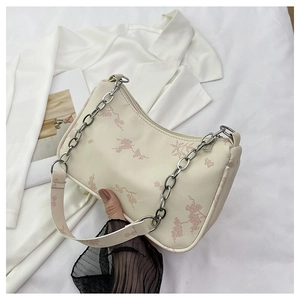 Close-up of cream underarm bag featuring pink floral print and silver chain detail