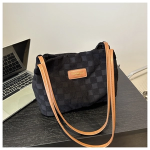 Detail of black checkered nylon tote bag with brown leather strap and brand label
