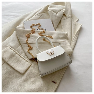 Close-up of white mini square bag featuring a pearl-textured butterfly buckle and gold chain