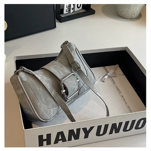 Close-up of gray textured leather shoulder bag featuring a square silver buckle in a box